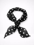 Black polka dot scarf with a rose brooch on a white background