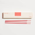 Red incense sticks in front of a white box with 'Mokko' branding on a light gray background