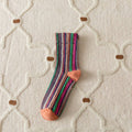 Striped sock with orange toes on a textured white surface