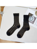 Black sheer socks on a white surface with a magazine underneath