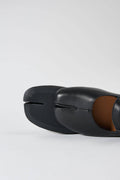 Black open-toe shoes with a brown interior on a light gray background