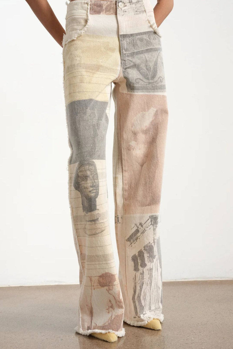 Person wearing patchwork pants with printed patterns on a plain background
