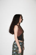 Woman wearing a brown top and camouflage pants against a white background