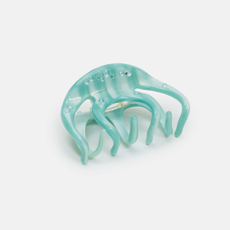 Turquoise hair clip on a light gray background