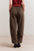 Person wearing brown pants and a red top against a plain background
