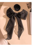 Black polka dot scarf with a large bow on a beige surface