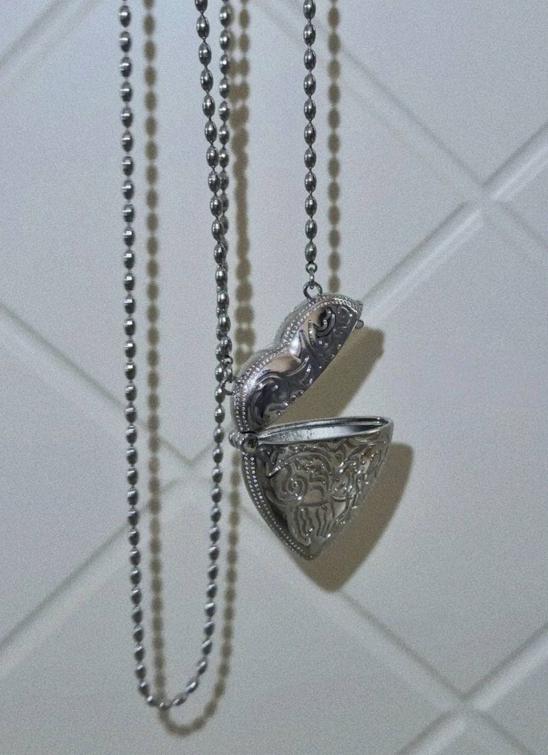 Silver necklace with a decorative pendant on a tiled wall background