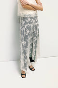 Person wearing a long, light-colored floral skirt against a white background