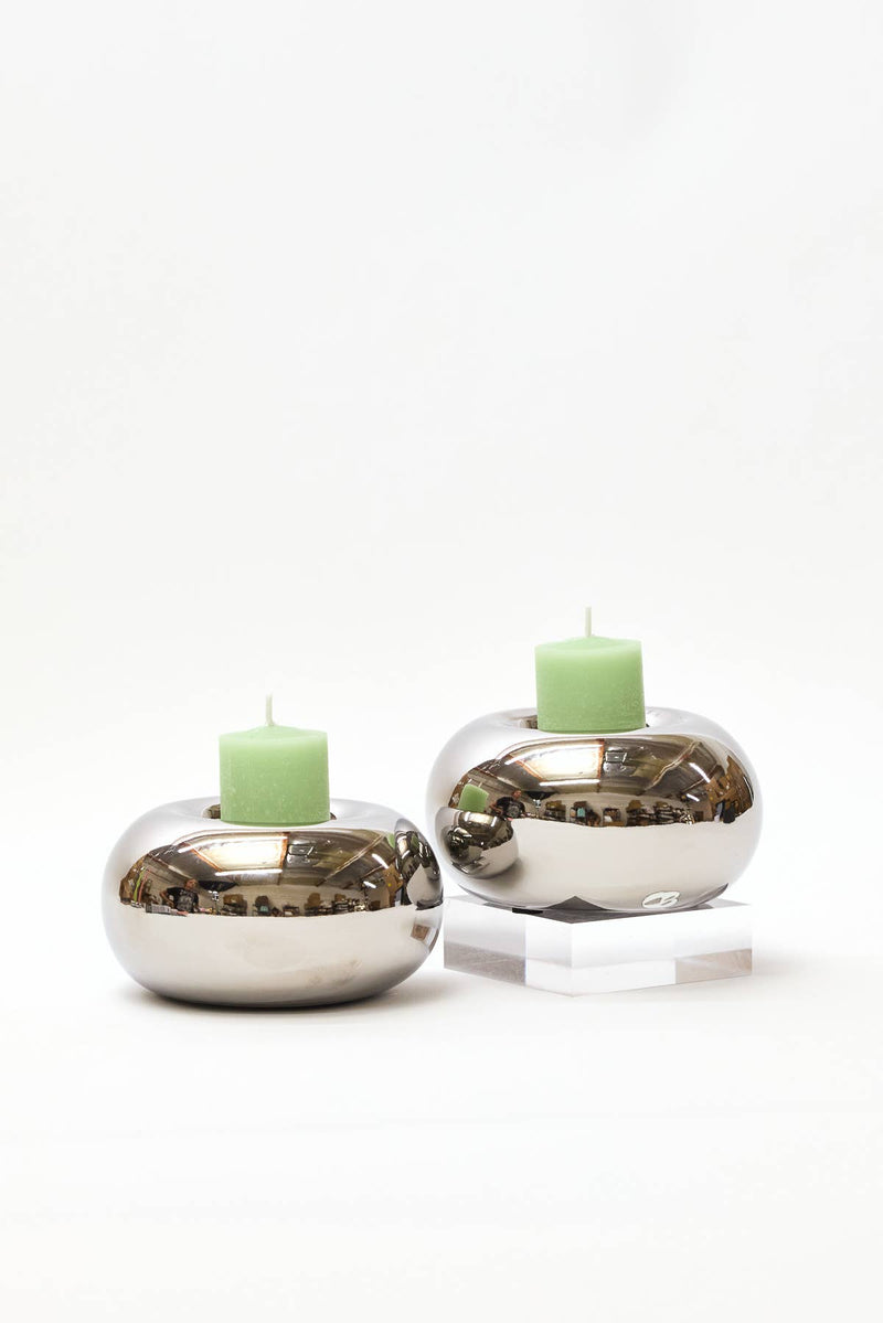 Two silver candle holders with green candles on a white background