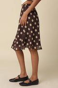 Person wearing a brown polka dot skirt on a beige background