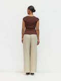 Person wearing a brown top and beige pants on a white background