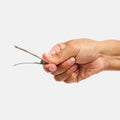 Hand holding a small tool against a light gray background