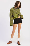 Person wearing a yellow and black striped sweater with black shorts on a white background