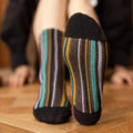 Striped socks with black toes and heels on a wooden floor.