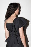 Black off-shoulder dress with ruffled details on a white background