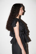 Woman wearing a black ruffled dress against a white background