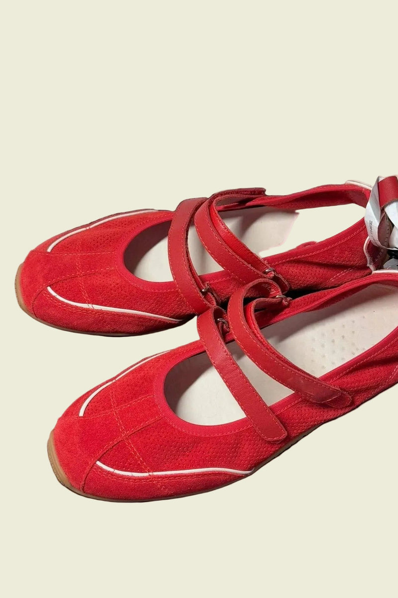 Red shoes with white soles on a black surface
