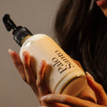 Person holding a bottle of Palo Santo lotion with a neutral background