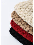 Stack of four crocheted beanies in beige, brown, red, and black on a white background.