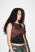 Woman wearing a brown and black sleeveless top with a white background