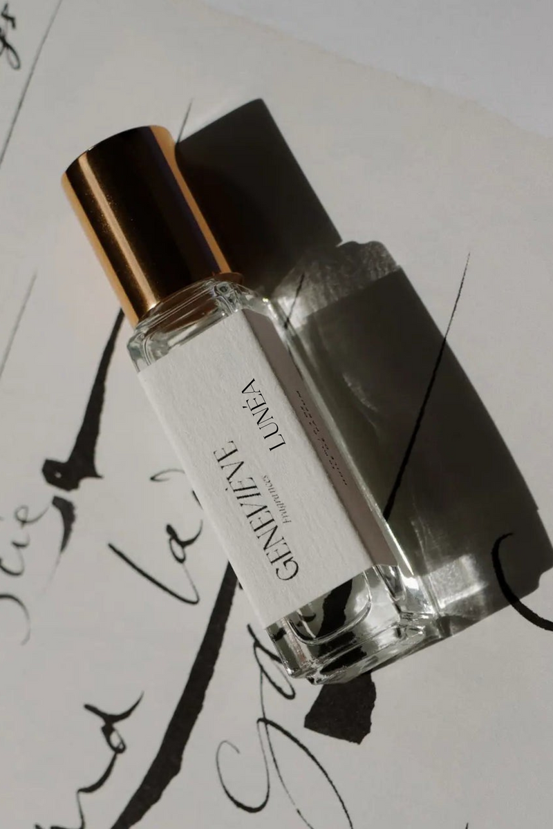 Perfume bottle labeled 'Geneve' on a sheet of music with cursive writing.