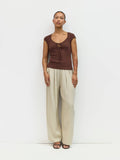 Woman wearing a brown top and beige pants against a white background