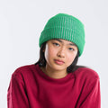 Person wearing a green knit beanie and red shirt against a white background