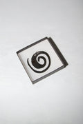 Small box with a black spiral design on a white background
