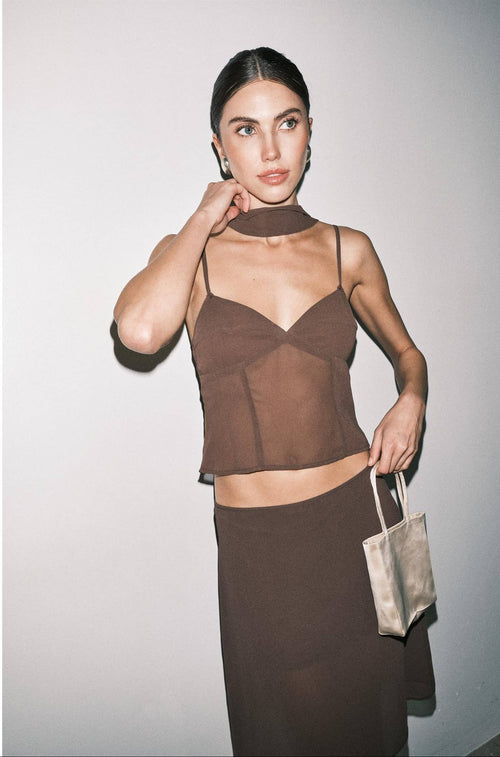 Woman wearing a brown sheer top and skirt set with a plain background