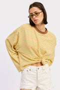 Person wearing a yellow striped sweater and white shorts on a plain background