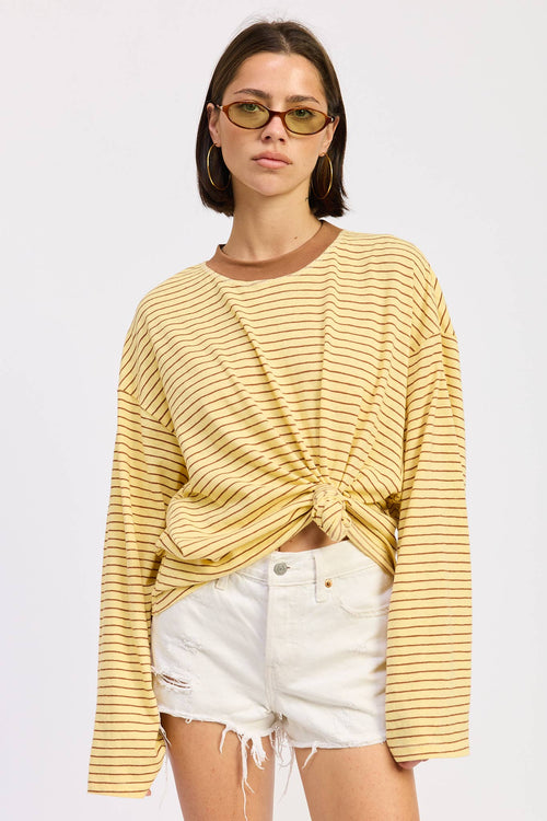 Woman wearing a yellow striped sweater and white shorts on a plain background