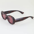 Sunglasses with tortoiseshell frame and red lenses on a white background