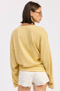 Person wearing a yellow striped sweater and white shorts on a plain background