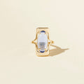 Gold ring with a central gemstone on a beige background