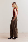 Woman wearing a red top and brown wide-leg pants against a white background