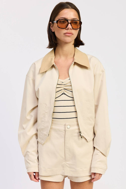 Woman wearing a beige jacket over a striped dress on a white background