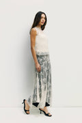 Woman wearing a sleeveless top and floral skirt against a white background