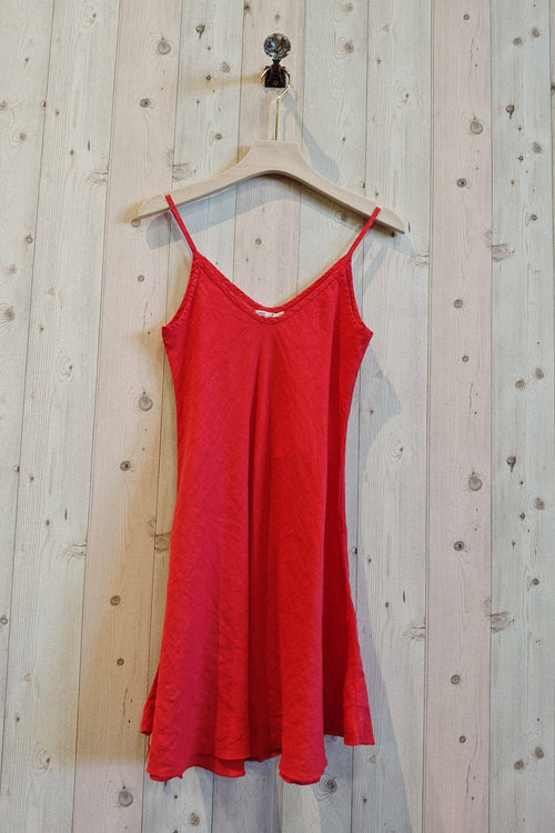 Red dress hanging on a wooden hanger against a wooden wall.