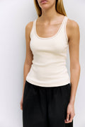 Person wearing a white tank top and black pants against a plain background