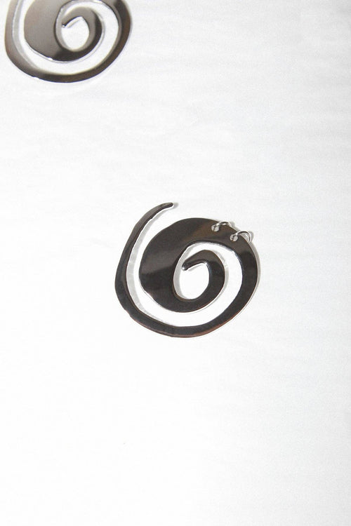 Metallic spiral earrings on a light gray background