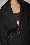 Black coat with studded details and a brown leather bag worn by a person.