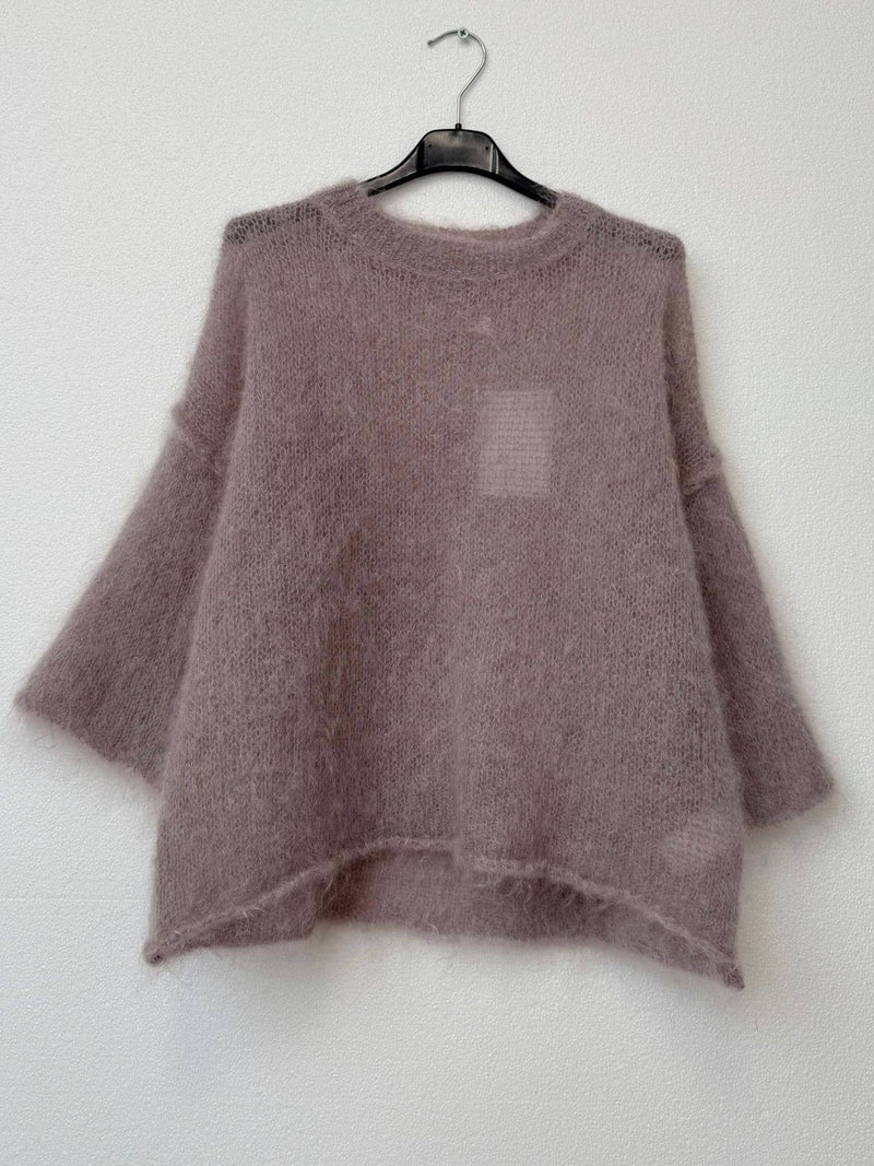 Mauve sweater on a hanger against a white wall