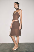 Woman wearing a brown dress with a sheer overlay against a plain background