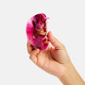 Hand holding a pink and red agate stone against a white background
