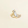 Gold ring with a central gemstone on a beige background