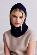 Woman wearing a dark blue knitted hood over a beige sweater against a white background