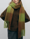 Person wearing a green and brown gradient scarf on a plain background