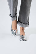 Silver shoes worn with rolled-up gray jeans on a white background