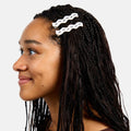Person with braided hair wearing a decorative hair clip on a plain background