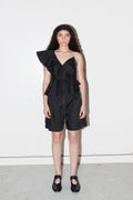 Woman wearing a black outfit with ruffled details against a white background